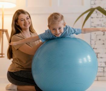 Kleiner Junge macht Balanceübungen auf einem großen Ball